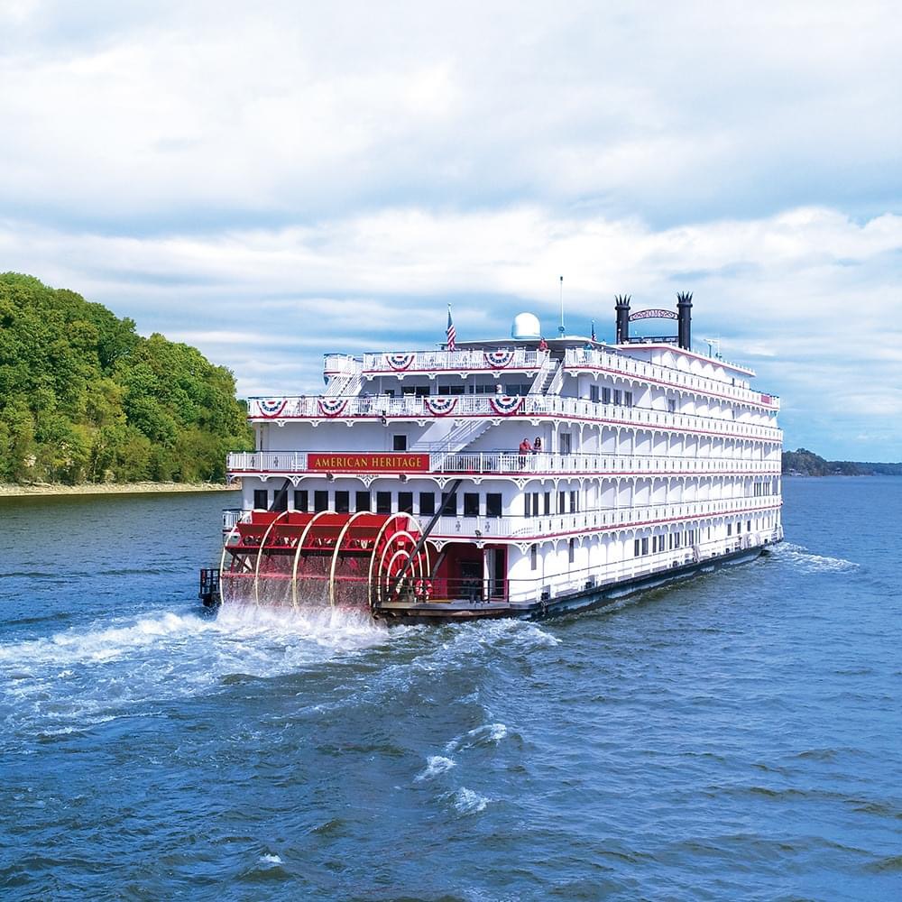 An American Heritage Cruise sailing by a shore.